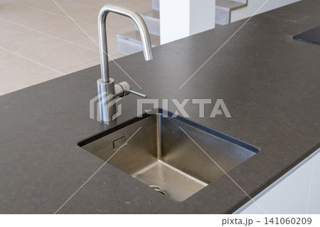 Modern kitchen island with a sleek stainless steel sink and faucet Modern kitchen island with a sleek stainless steel sink and faucet 141060209