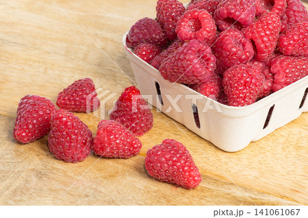 Fresh ripe raspberries in paper baskets on a wooden table, healthy organic summer berries. Fresh ripe raspberries in paper baskets on a wooden table, healthy organic summer berries. 141061067
