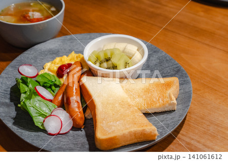 トースト、ソーセージ、スクランブルエッグ、サラダ、フルーツが並べられた豪華な朝食プレートとスープの全 トースト、ソーセージ、スクランブルエッグ、サラダ、フルーツが並べられた豪華な朝食プレートとスープの全 141061612
