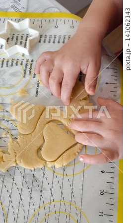 top view of children cutting gingerbread cookies from metal molds 141062143