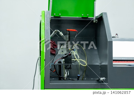 Common rail diesel fuel injector installed inside diagnostic test bench chamber for automated testing and calibration 141062857