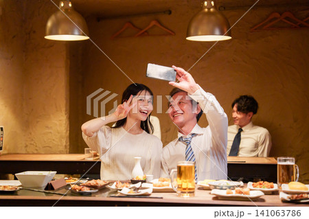 居酒屋で自撮りをする高齢男性と若い女性 居酒屋で自撮りをする高齢男性と若い女性 141063786
