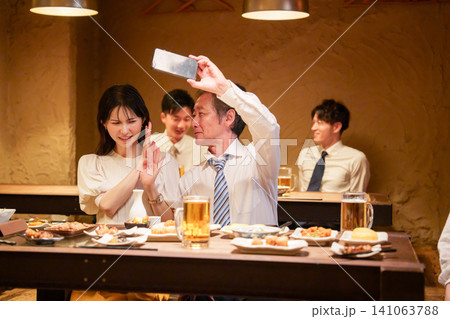 居酒屋で自撮りをする高齢男性と若い女性 居酒屋で自撮りをする高齢男性と若い女性 141063788