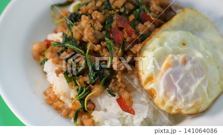 stir fried pork with holy basil on top with fried egg on cooked rice stir fried pork with holy basil on top with fried egg on cooked rice 141064086