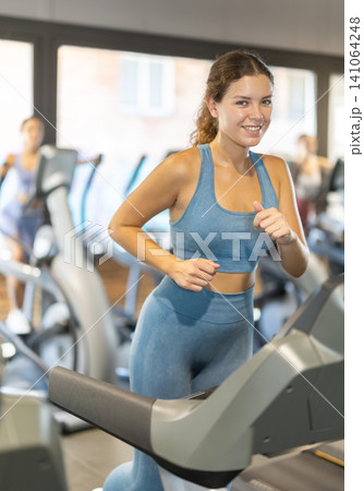 Positive young girl training on treadmill in gym 141064248