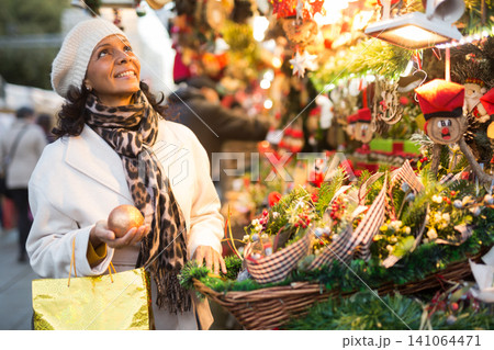 Woman choosing christmas decorations at fair Woman choosing christmas decorations at fair 141064471