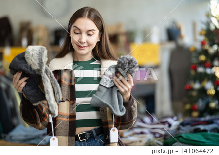 Woman client looks at products in store, choose closely ladys arm hat 141064472