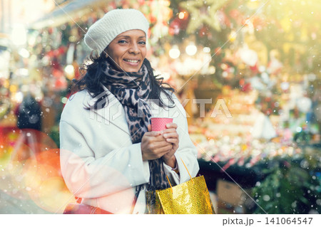 Happy woman with coffee over christmas tree lights outdoors Happy woman with coffee over christmas tree lights outdoors 141064547