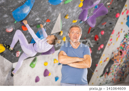 Adult man posing on climbing wall Adult man posing on climbing wall 141064609