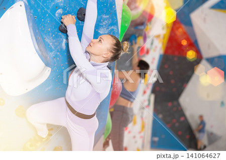 Adult woman practicing rock climbing on climbing wall Adult woman practicing rock climbing on climbing wall 141064627