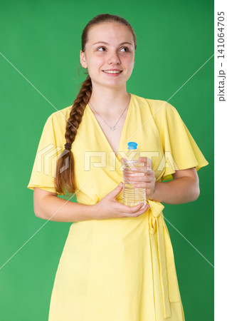 Teenage girl drinking water in front of green screen 141064705