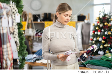 Uncertain young woman choosing socks in clothing store 141064914