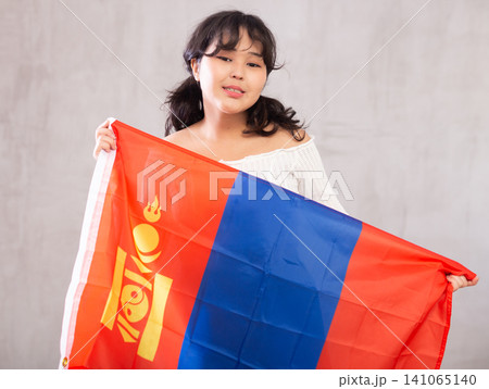 Smiling young girl holding flag of Mongolia Smiling young girl holding flag of Mongolia 141065140