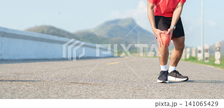 Young adult male runner with knee pain from ACL injury or patellofemoral syndrome. Man having joint ache, ligament tear or patellar tendinitis during running. Sports medical and healthcare concept 141065429