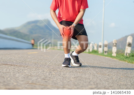 Young adult male runner with knee pain from ACL injury or patellofemoral syndrome. Man having joint ache, ligament tear or patellar tendinitis during running. Sports medical and healthcare concept Young adult male runner with knee pain from ACL injury or patellofemoral syndrome. Man having joint ache, ligament tear or patellar tendinitis during running. Sports medical and healthcare concept 141065430