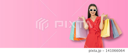 Woman smiles while holding colorful shopping bags in space Woman smiles while holding colorful shopping bags in space 141066064