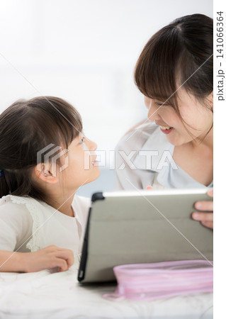 勉強がわかった!と見つめ合って喜ぶ、タブレットを使って一緒に学習する母親と小学生の女の子・家庭で学ぶ 勉強がわかった!と見つめ合って喜ぶ、タブレットを使って一緒に学習する母親と小学生の女の子・家庭で学ぶ 141066364