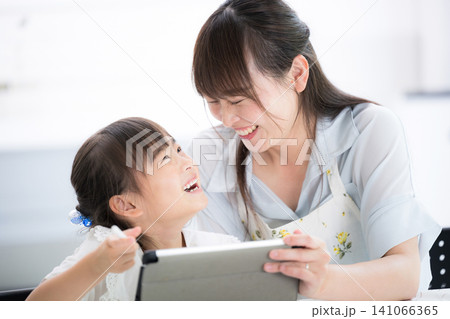 勉強がわかった!と見つめ合う喜ぶ、タブレットを使って一緒に学習する母親と小学生の女の子・家庭で学ぶ 勉強がわかった!と見つめ合う喜ぶ、タブレットを使って一緒に学習する母親と小学生の女の子・家庭で学ぶ 141066365
