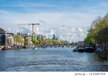 Scenic Amstel River view with historic architecture and boats in Amsterdam, The Netherlands Scenic Amstel River view with historic architecture and boats in Amsterdam, The Netherlands 141066704