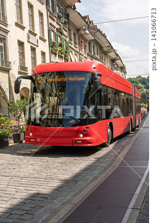 Modern red electric bus driving on a historic cobblestone street in Bern city center Switzerland Modern red electric bus driving on a historic cobblestone street in Bern city center Switzerland 141066713