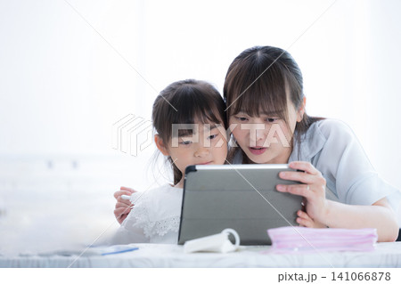 タブレットを見ながらインターネットのトラブルについて確認する親子・情報モラルを学ぶ母親と小学生の女の タブレットを見ながらインターネットのトラブルについて確認する親子・情報モラルを学ぶ母親と小学生の女の 141066878