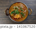 Indian curry dish in a metal bowl with herbs and vegetables 141067520