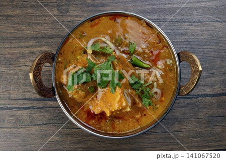 Indian curry dish in a metal bowl with herbs and vegetables Indian curry dish in a metal bowl with herbs and vegetables 141067520