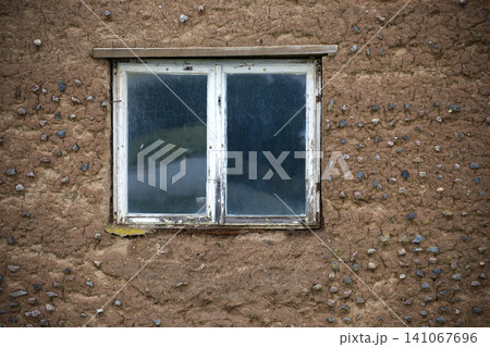 Weathered White Window Set in Rustic Mud Wall of Old Rural Building With Pebble Texture Weathered White Window Set in Rustic Mud Wall of Old Rural Building With Pebble Texture 141067696