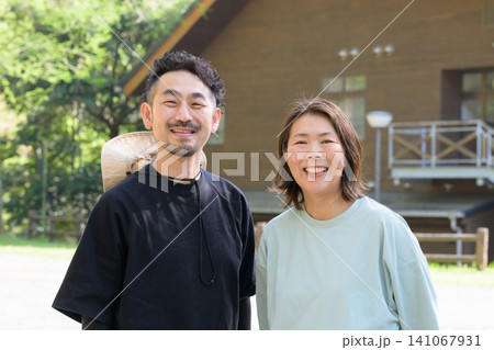 ペンション前に立つ笑顔の夫婦オーナー 141067931