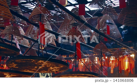Smoke wafting from spiral incense coils hanging from the ceiling with red tags decoration for Lunar New Year in Man Mo Temple. Sheung Wan, Hong Kong 141068806