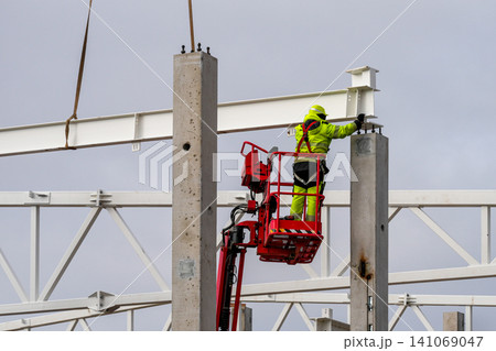 Worker installing steel beam on concrete column using aerial lift during construction project Worker installing steel beam on concrete column using aerial lift during construction project 141069047