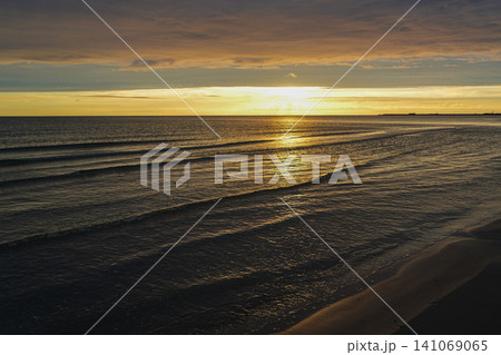 Golden Sunset Over the Baltic Sea with Gentle Waves and Sandy Shoreline Under Dramatic Evening Sky View Golden Sunset Over the Baltic Sea with Gentle Waves and Sandy Shoreline Under Dramatic Evening Sky View 141069065