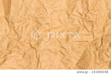 Crumpled brown kraft paper texture background. Full frame close up of wrinkled recycled paper sheet. Concept for eco friendly package material, abstract background and vintage design Crumpled brown kraft paper texture background. Full frame close up of wrinkled recycled paper sheet. Concept for eco friendly package material, abstract background and vintage design 141069198