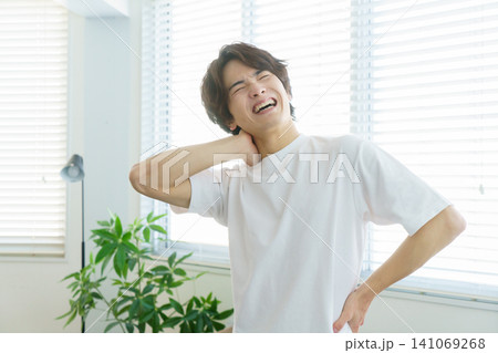 窓際でストレッチをしながら首を抑える若い日本人男性 141069268