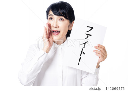 ファイトと書かれた紙を持ち掛け声をかけ応援する白いシャツを着た中年女性 ファイトと書かれた紙を持ち掛け声をかけ応援する白いシャツを着た中年女性 141069573