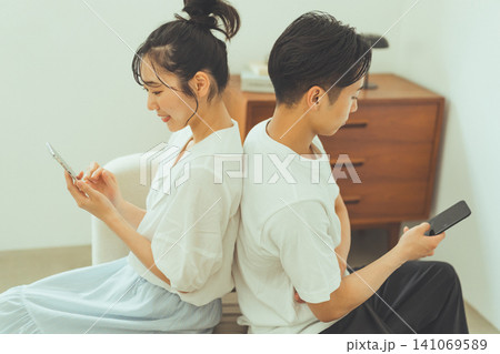 スマホを見つめる背中合わせのカップル 141069589