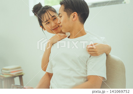男性の頬に顔を近づけて笑顔の女性カップル 男性の頬に顔を近づけて笑顔の女性カップル 141069752