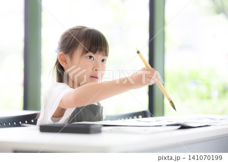 書道に集中して筆で文字を書く小学生の女の子・習字を学ぶ日本の子ども　真剣な表情 141070199