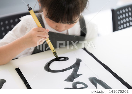書道に集中して筆文字を書く小学生の女の子・習字を学ぶ日本の子ども 141070201