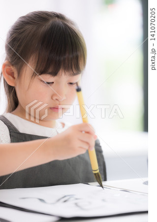 書道に集中して筆で文字を書く小学生の女の子・習字を学ぶ日本の子どものクローズアップ縦 書道に集中して筆で文字を書く小学生の女の子・習字を学ぶ日本の子どものクローズアップ縦 141070205