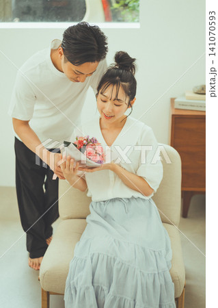 花束を受け取り微笑む女性と覗き込む男性カップル 花束を受け取り微笑む女性と覗き込む男性カップル 141070593