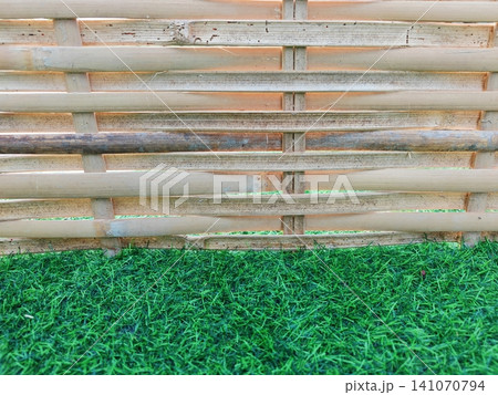 Bamboo woven fence background with green artificial grass foreground. Bamboo woven fence background with green artificial grass foreground. 141070794