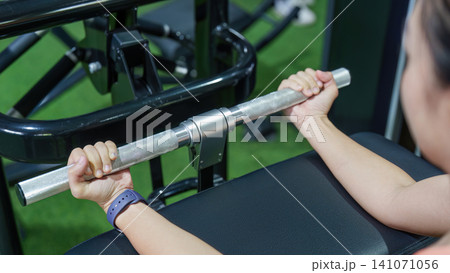 Cropped hands gripping metal bar of exercise machine in gym for strength training workout Cropped hands gripping metal bar of exercise machine in gym for strength training workout 141071056