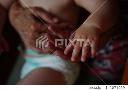 Elderly and Baby Hands Touching in a Moment of Connection Elderly and Baby Hands Touching in a Moment of Connection 141071069