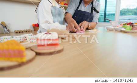 Asian grandmother and granddaughter kneading dough together in kitchen for family baking Asian grandmother and granddaughter kneading dough together in kitchen for family baking 141071242