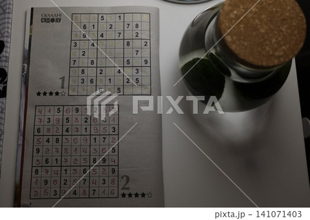 Handwritten numbers fill a Sudoku grid on a paper from a puzzle book Handwritten numbers fill a Sudoku grid on a paper from a puzzle book 141071403