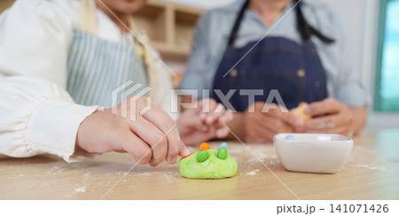Cropped hand of child decorating green cookie dough with colorful candies Cropped hand of child decorating green cookie dough with colorful candies 141071426
