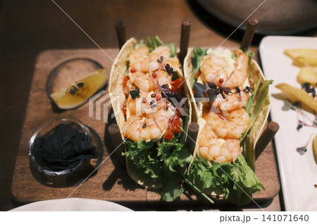 Two vibrant shrimp tacos filled with fresh lettuce and plump shrimp Two vibrant shrimp tacos filled with fresh lettuce and plump shrimp 141071640