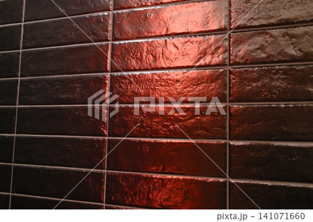 Dark rectangular tiles reflect vibrant red light, accentuating rough texture and grout lines Dark rectangular tiles reflect vibrant red light, accentuating rough texture and grout lines 141071660