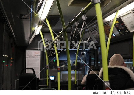 Passengers travel inside a public bus during evening hours. Passengers travel inside a public bus during evening hours. 141071687